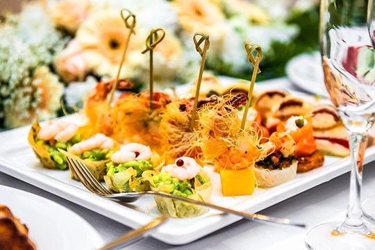 Bridal shower guests filling plates from brunch buffet with pastries and fruit