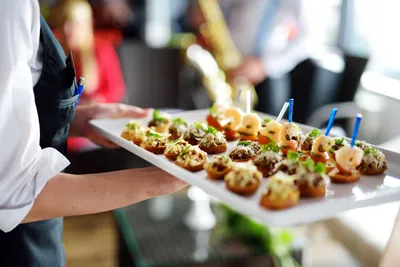 Cocktail glasses and appetizers displayed on bar counter at evening event
